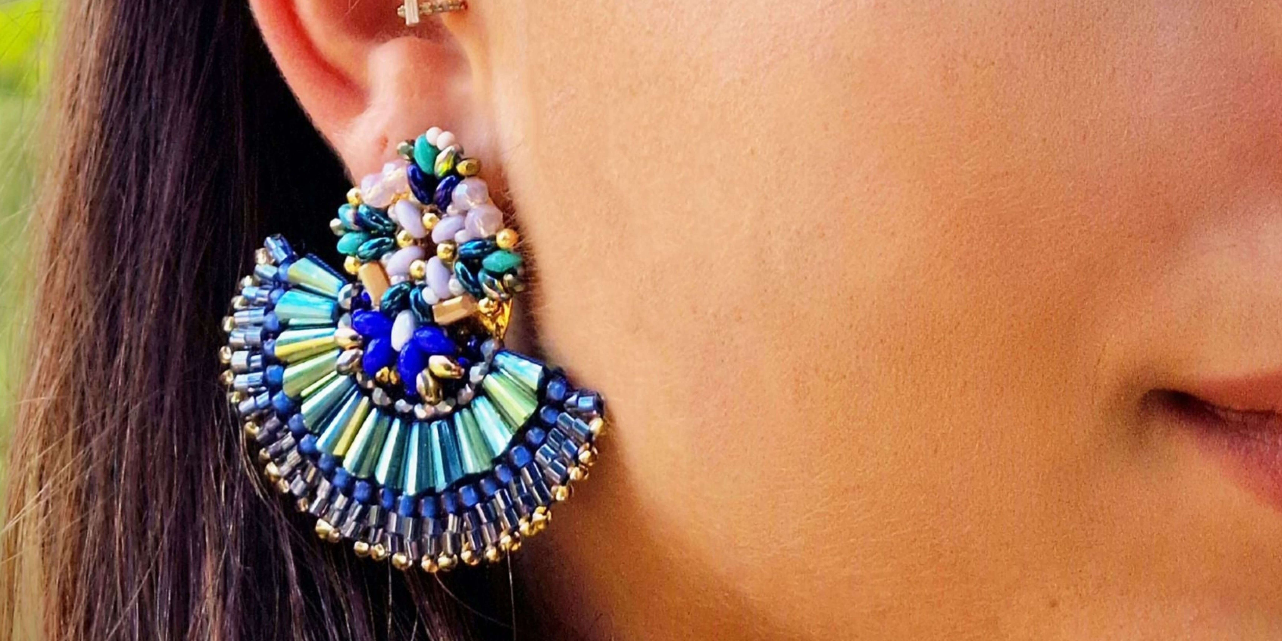 Close-up of a woman’s ear with a Marakame handwoven earring, featuring a blue and turquoise glass beads in a half moon design, made in Mexico