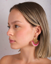 Woman wearing Mayana Designs Beaded Handwoven Flamenco Fan Earrings in Pink, profile view showcasing vibrant beadwork and brass accents