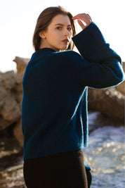 Woman in a petrol blue cashmere sweater by Nuage Cashmere, side view highlighting the wide sleeves and soft fit