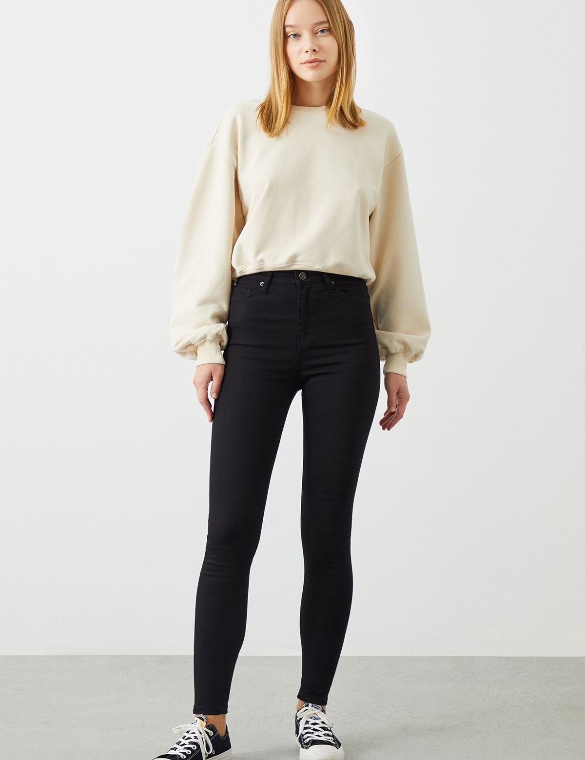 Stylish outfit featuring black slim jeans from sustainable brand RA Denim paired with an off-white organic cotton sweater.