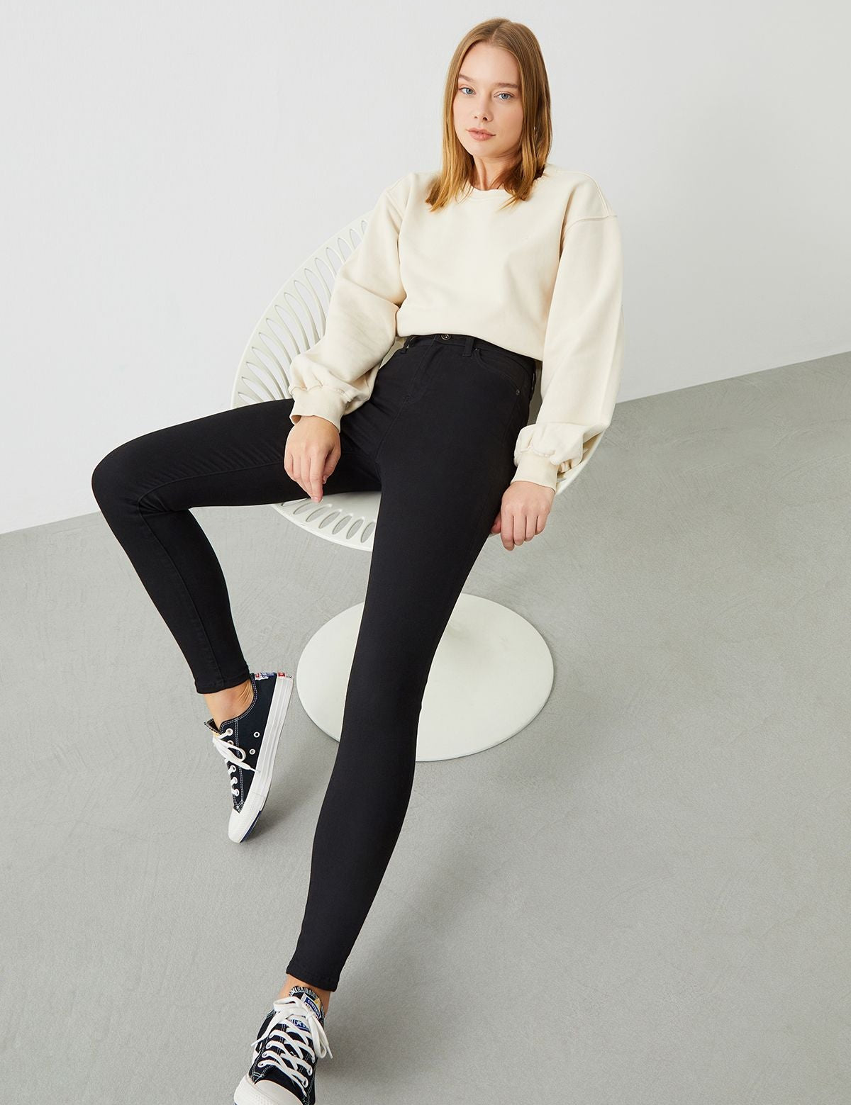 A woman wearing the sustainable Black Slim Jeans, emphasizing their flattering super skinny fit.