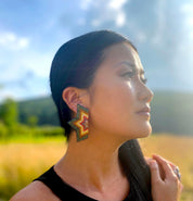 A woman wearing the Beaded Handwoven Large Half Star Earrings in Emerald