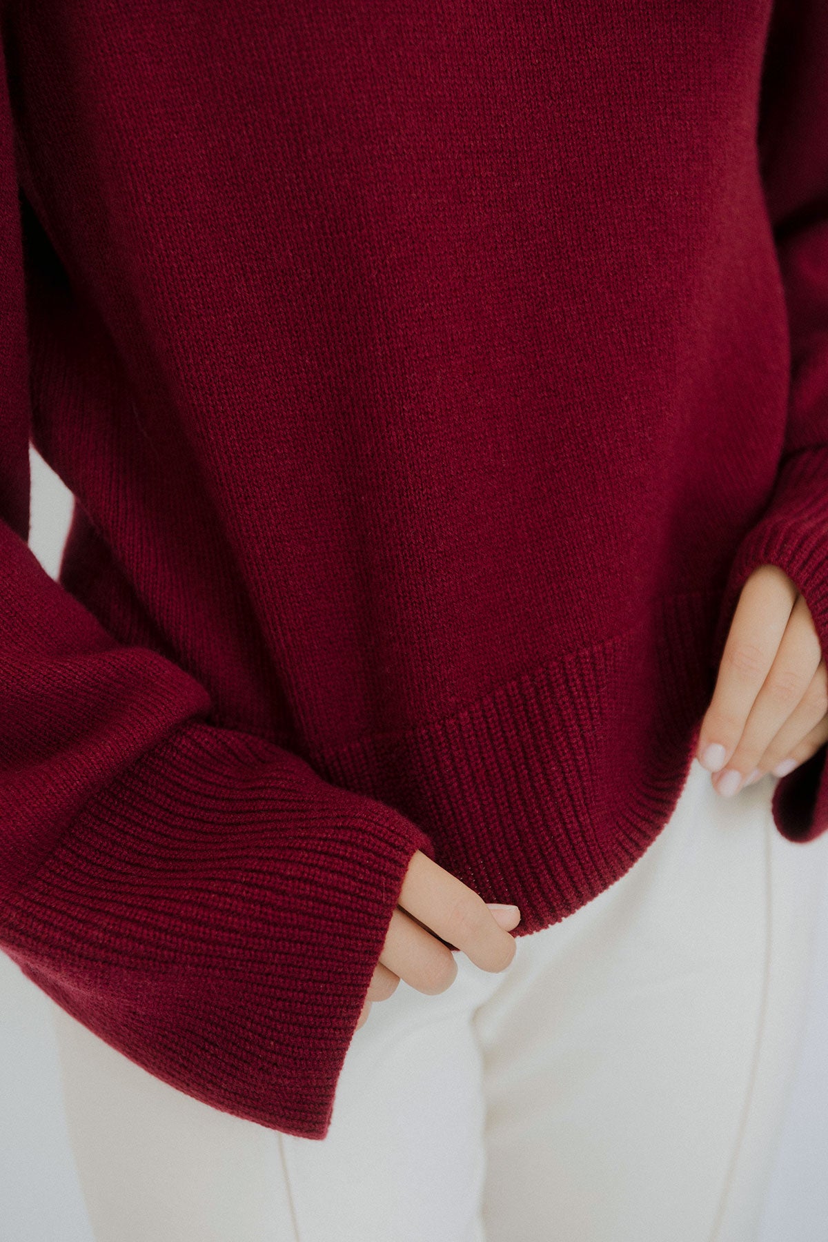 Close-up of a women’s burgundy cashmere sweater by Nuage Cashmere, highlighting the soft, knitted texture and luxurious 100% cashmere fabric in a warm red tone