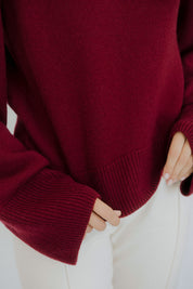 Close-up of a women’s burgundy cashmere sweater by Nuage Cashmere, highlighting the soft, knitted texture and luxurious 100% cashmere fabric in a warm red tone