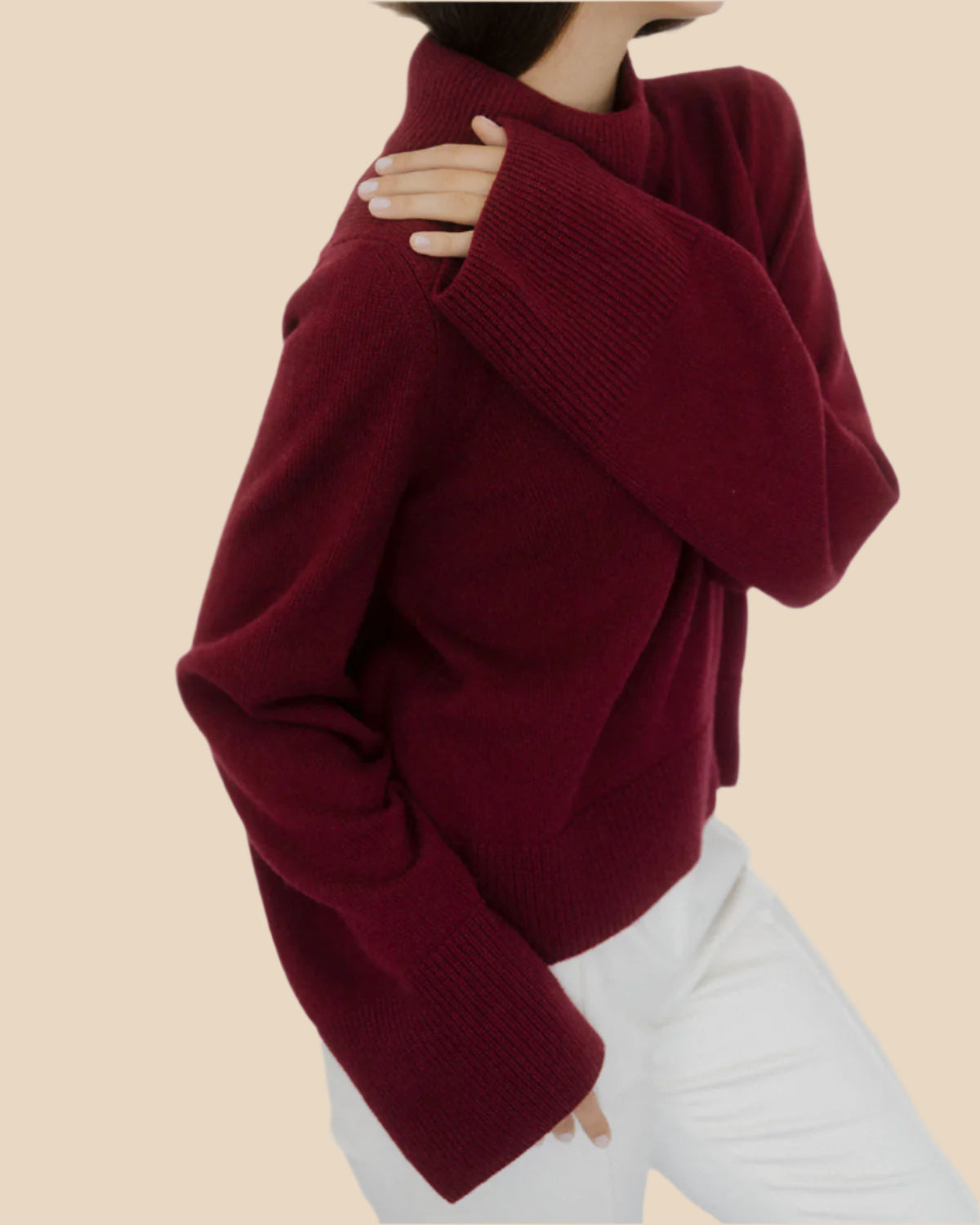 Side angle of a women’s burgundy cashmere sweater by Nuage Cashmere, showcasing its wide, long sleeves and lightweight, cozy design in a deep red shade.