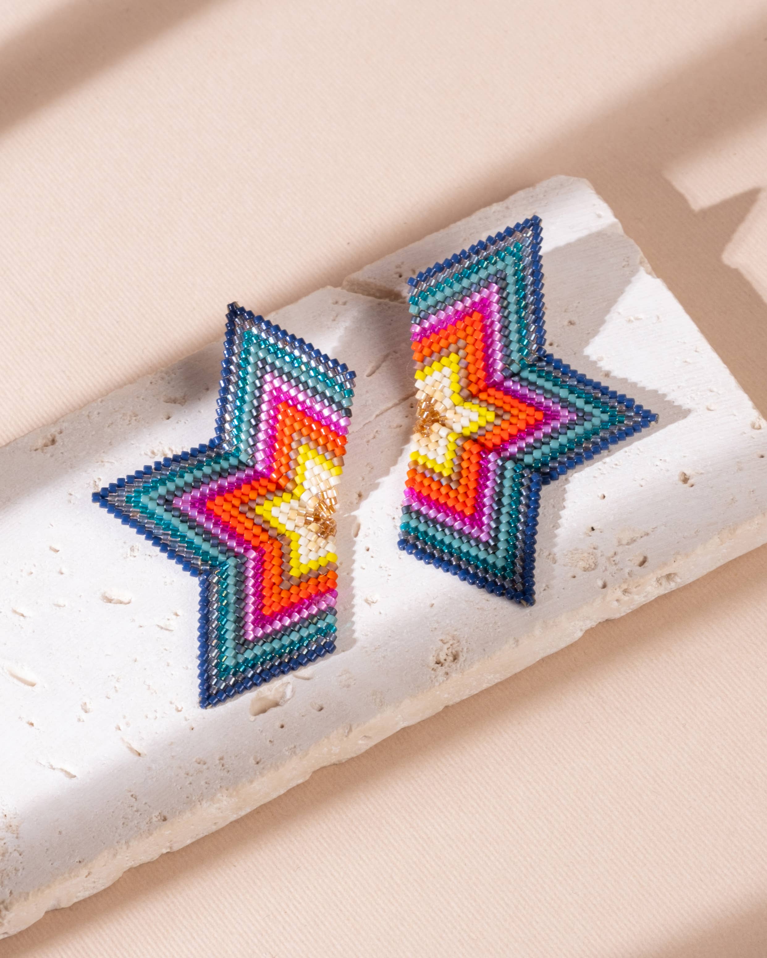 Handcrafted half-star earrings in red and emerald beads, showcasing the beautiful mix of colors and details in a bold design.