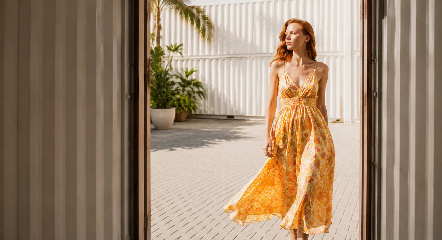 Woman wearing a yellow floral summer dress from 99things' independent designer dress collection
