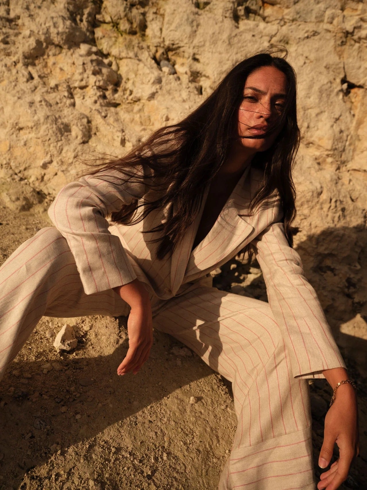 Mos Mosh summer collection – woman in tailored striped suit in sunlit natural setting.