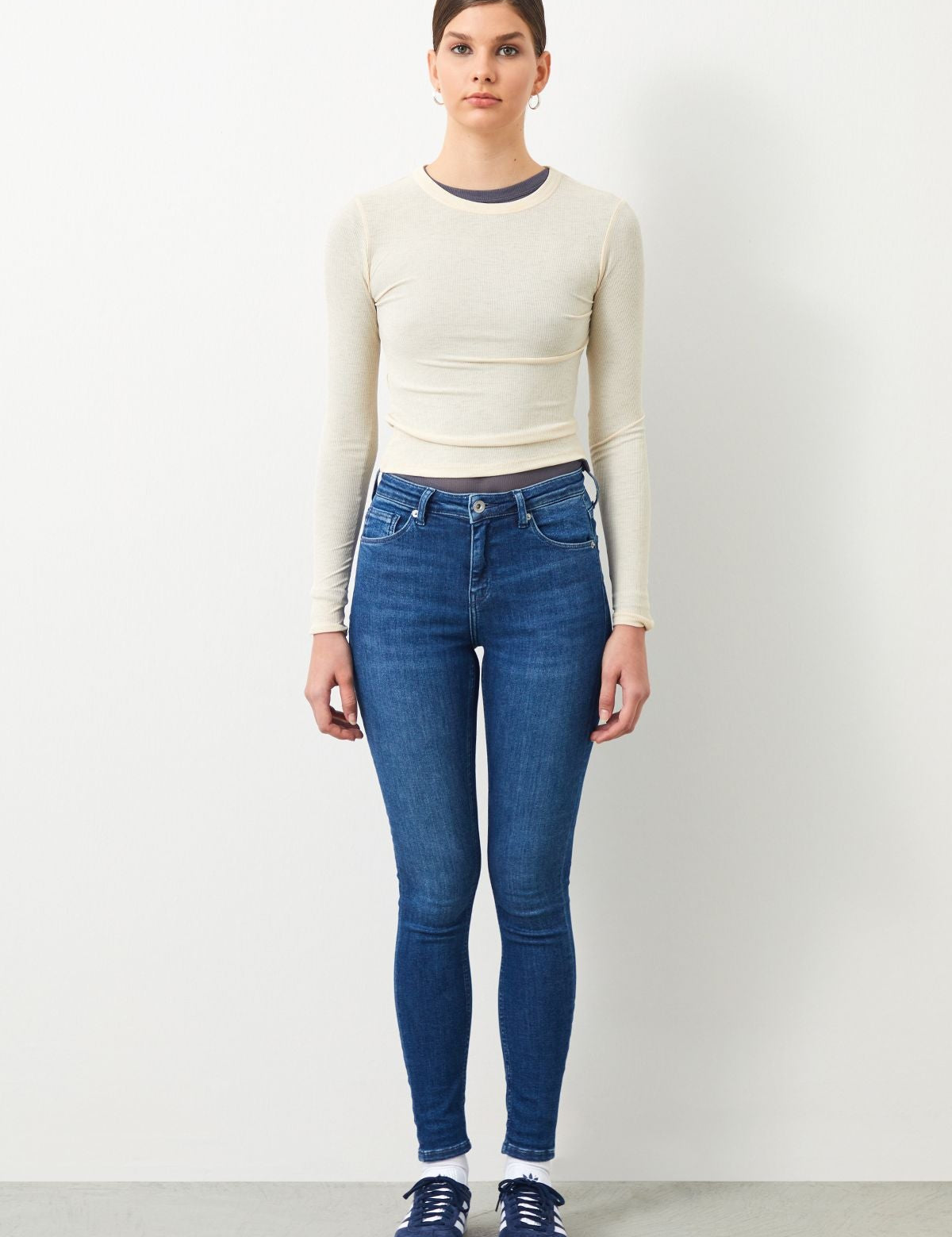Model wearing Sira Skinny Fit Dark Blue Women's Jeans with a tight white top, highlighting the perfect fit.
