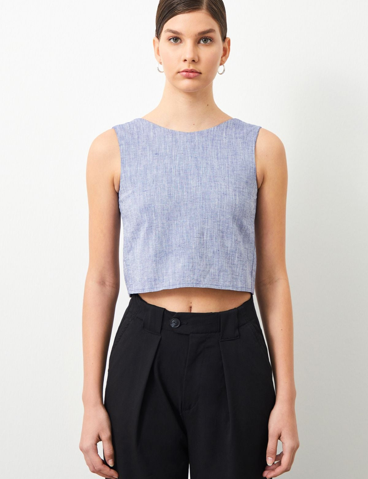 Stylish woman wearing PERLA Blue Linen Blouse, effortlessly pairing with black pants.