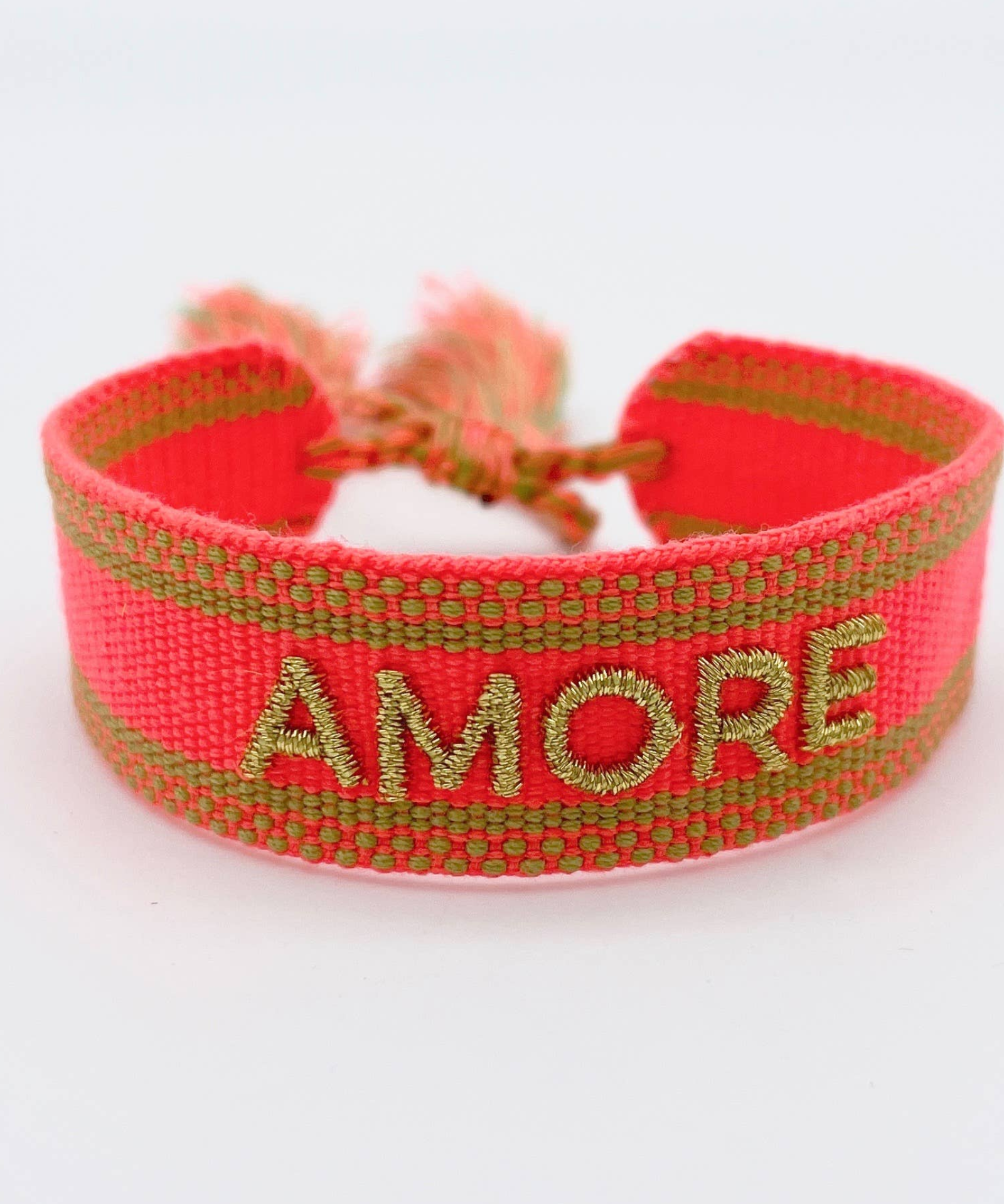 Close-up of adjustable neon orange woven friendship bracelet with green border and gold embroidered "AMORE" lettering and sliding knot cords.