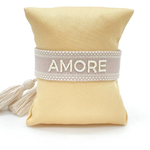 Close-up of adjustable soft taupe woven bracelet with embroidered “AMORE” lettering and sliding knot tassel cords.