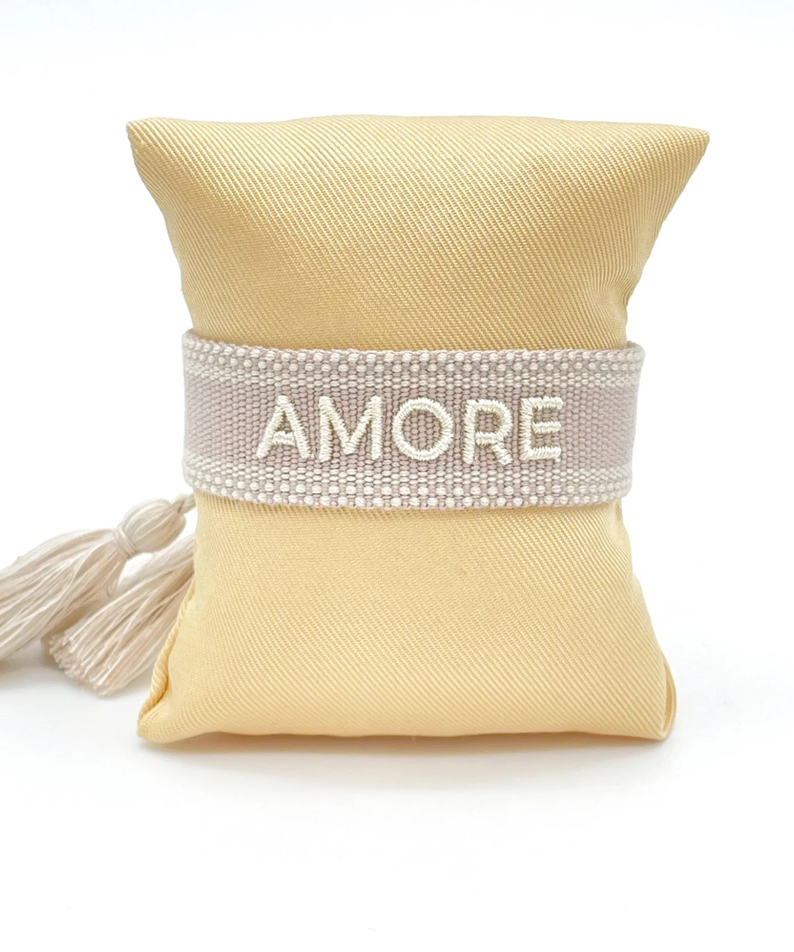 Close-up of adjustable soft taupe woven bracelet with embroidered “AMORE” lettering and sliding knot tassel cords.