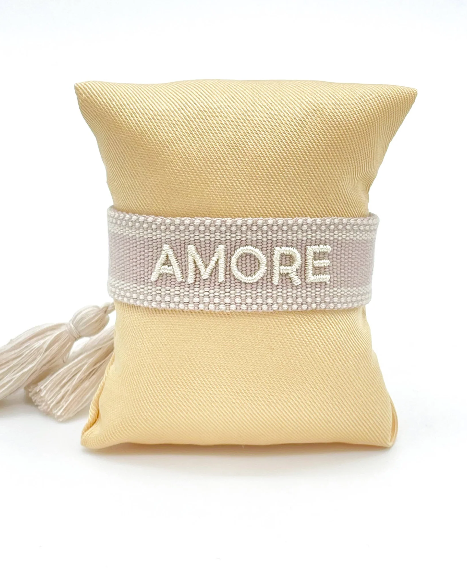 Close-up of adjustable soft taupe woven bracelet with embroidered “AMORE” lettering and sliding knot tassel cords.