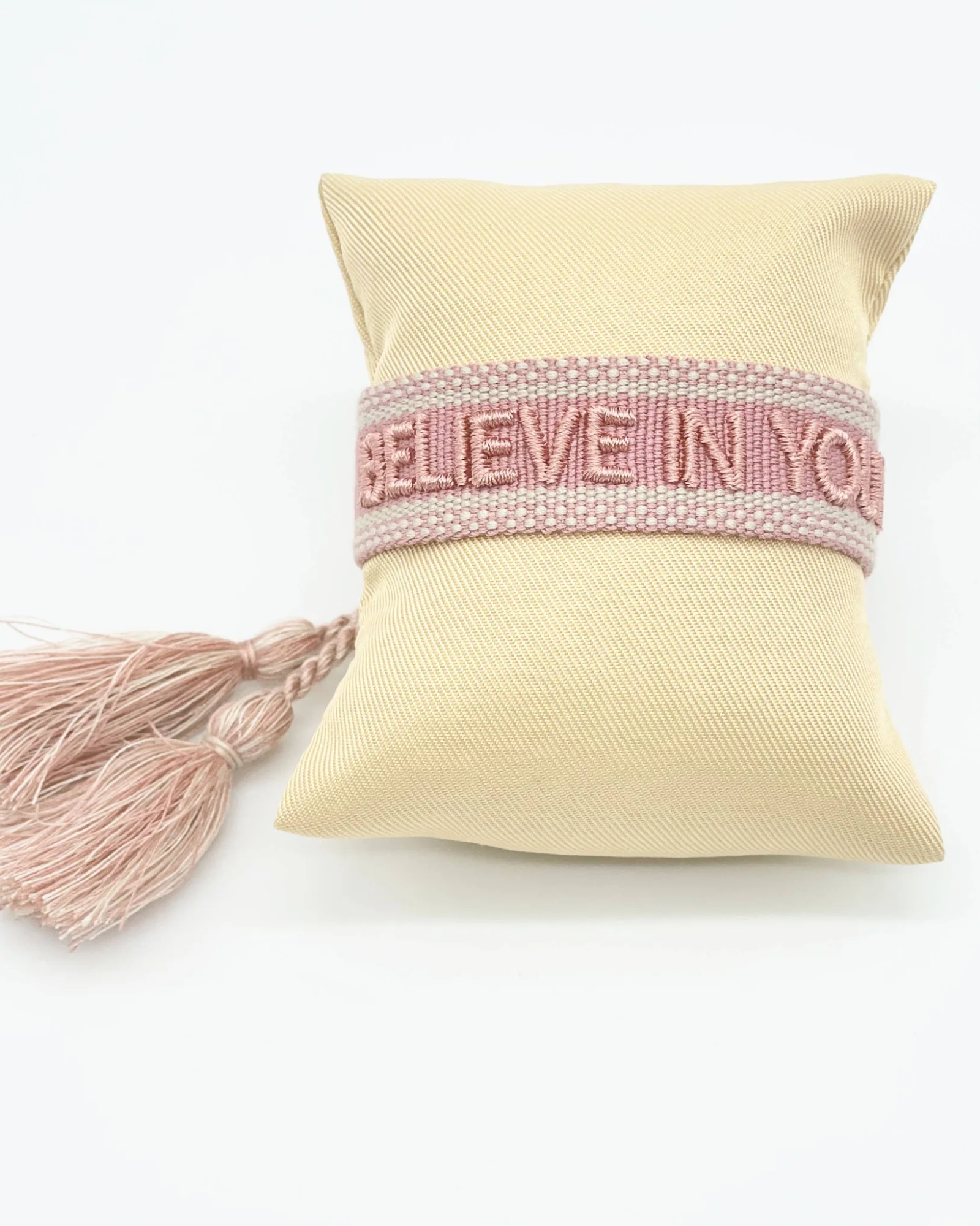 Close-up of adjustable vintage rose woven bracelet with embroidered “BELIEVE IN YOURSELF” lettering and sliding knot tassel cords.