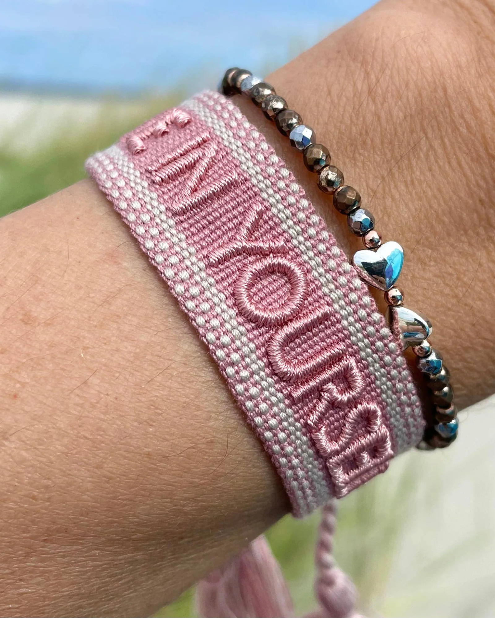 Close-up of adjustable vintage rose woven bracelet with embroidered “BELIEVE IN YOURSELF” lettering and sliding knot tassel cords.