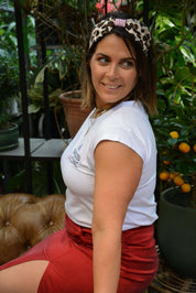 Woman wearing a white t-shirt and red skirt with a turban headband with leopard print 