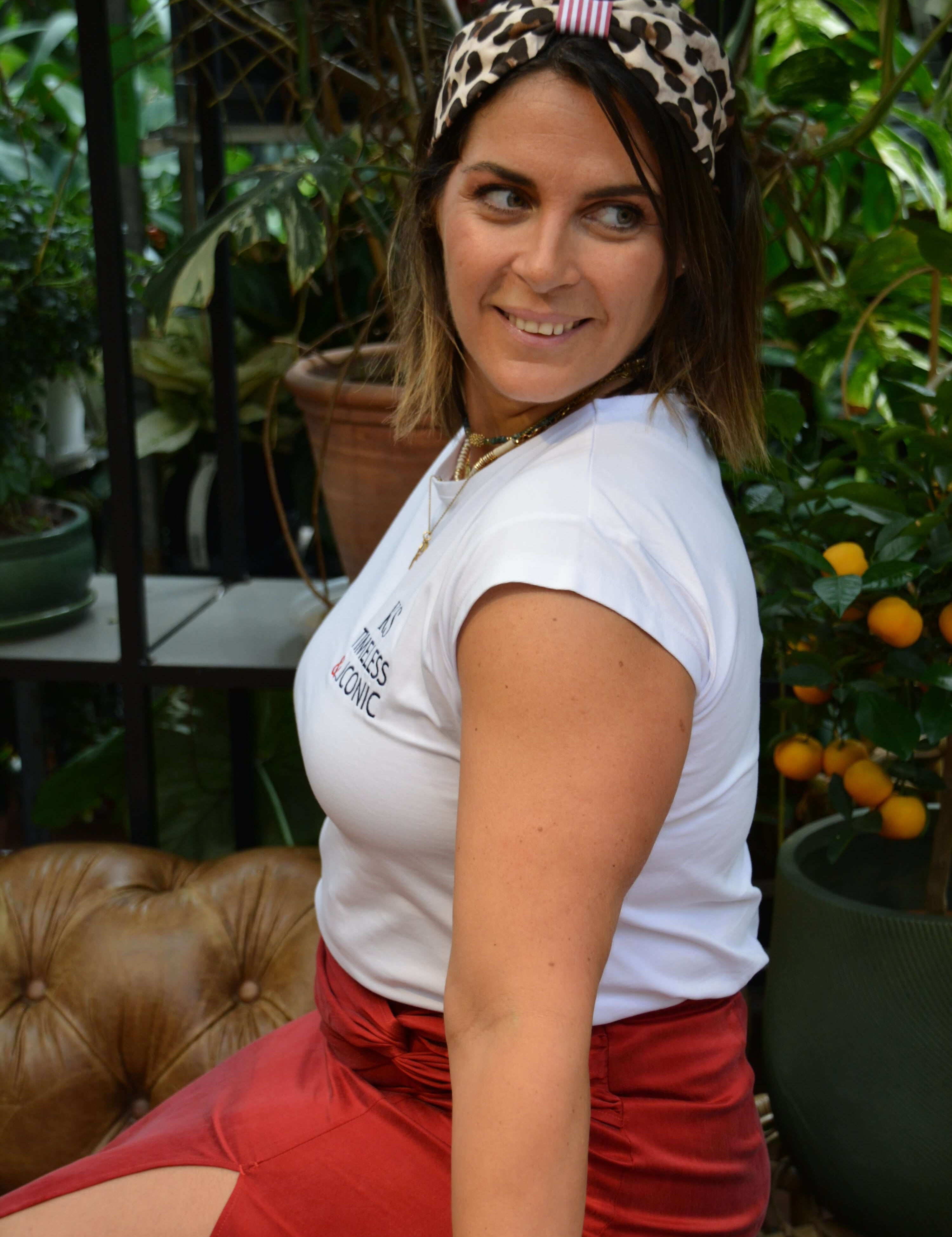 Woman wearing a white t-shirt and red skirt with a turban headband with leopard print 