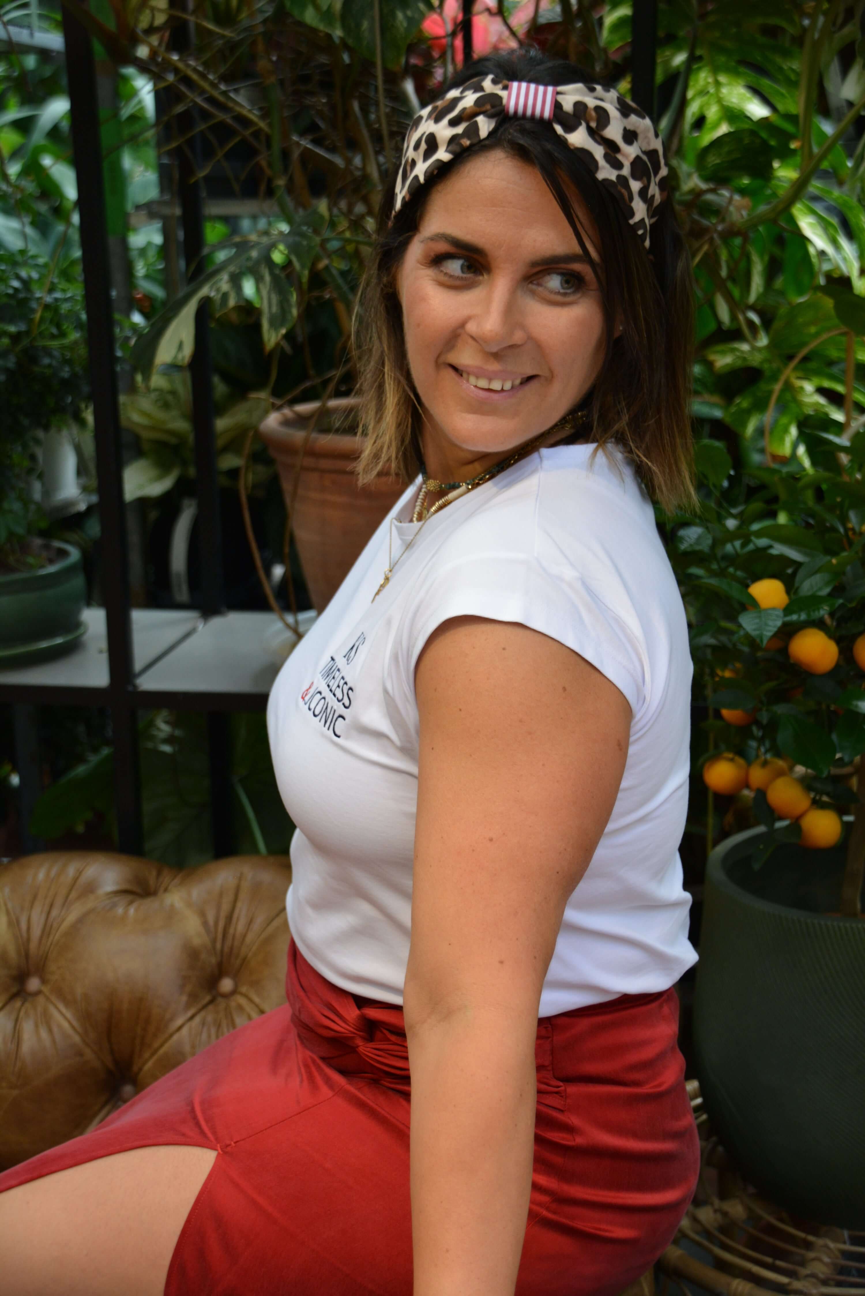 Woman wearing a white t-shirt and red skirt with a turban headband with leopard print 