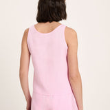 Person wearing a pink sleeveless top and pants on a light pink background
