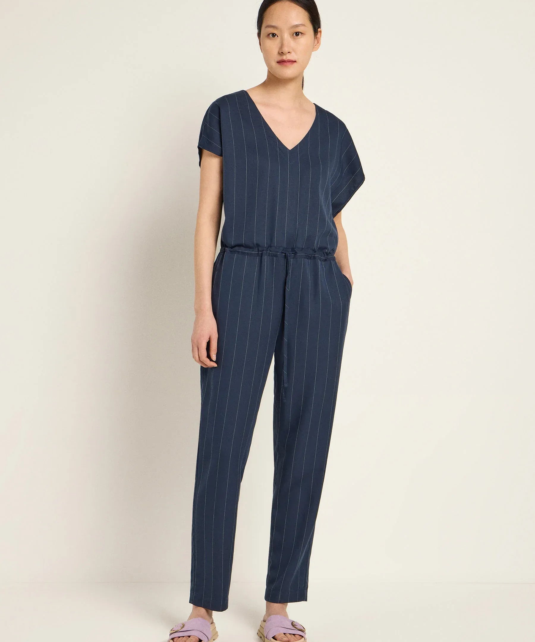 Woman wearing a navy blue striped jumpsuit by Lanius Fair Fashion - office essentials