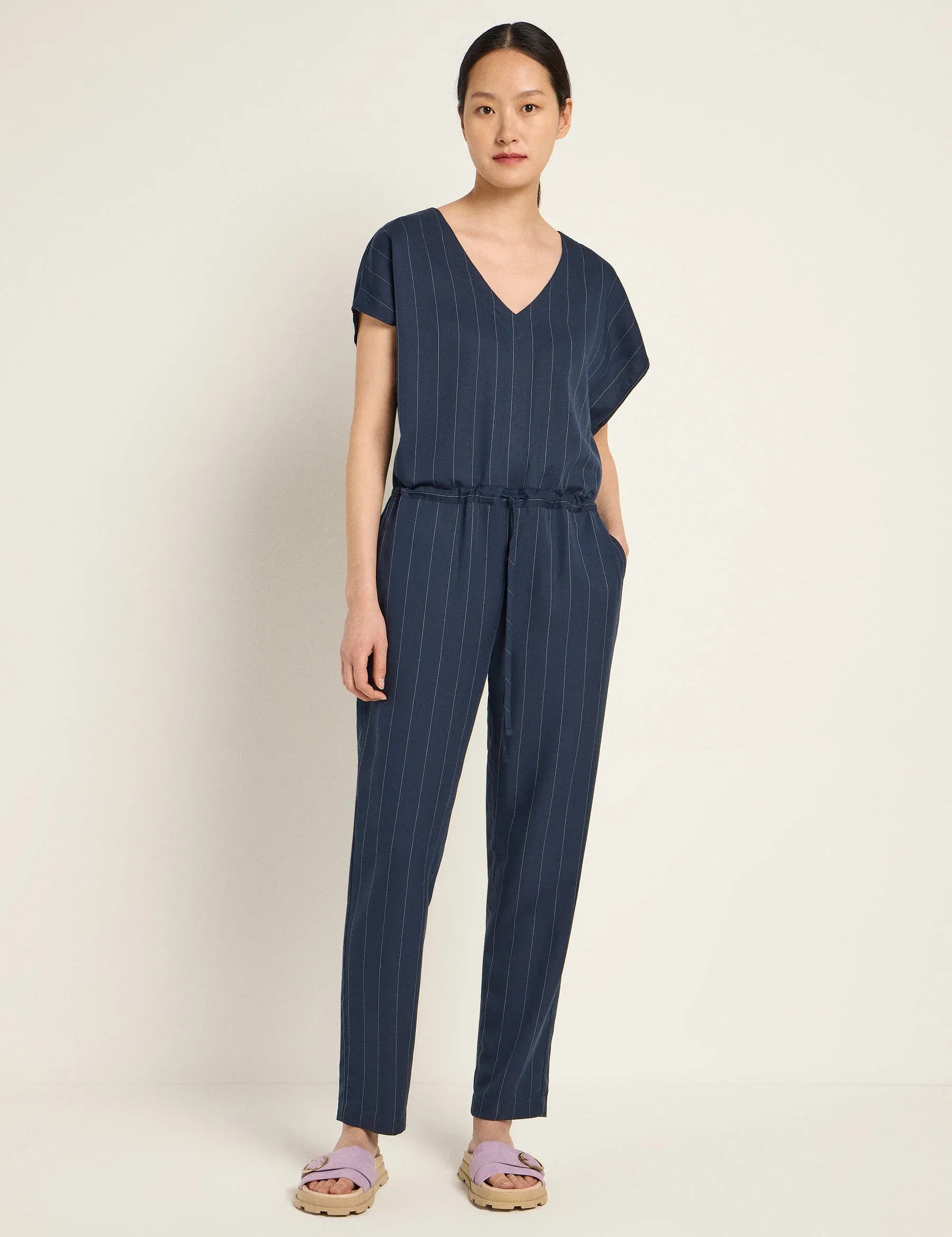 Woman wearing a navy blue striped jumpsuit by Lanius Fair Fashion - office essentials