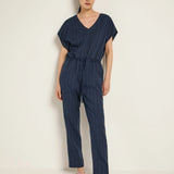 Woman wearing a navy pinstripe jumpsuit in a photo studio.