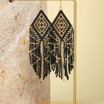Tribal Diamond Fringe Earrings in Black/Gold – Elegant beaded earrings displayed on a textured jewelry stand