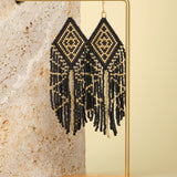 Tribal Diamond Fringe Earrings in Black/Gold – Elegant beaded earrings displayed on a textured jewelry stand