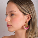 Woman wearing Mayana Designs Beaded Handwoven Flamenco Fan Earrings in Pink, profile view showcasing vibrant beadwork and brass accents