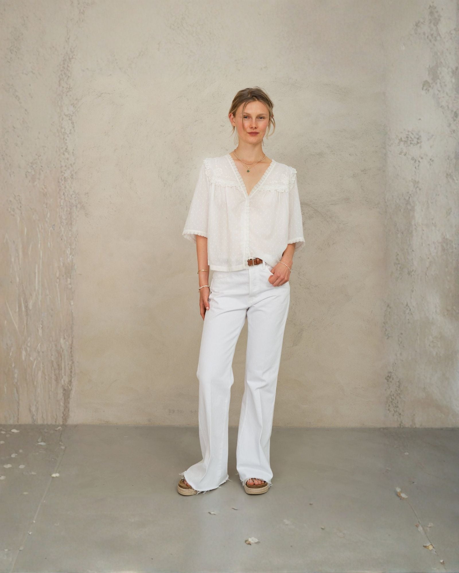 Model wearing white lace cotton blouse by Mabe Apparel with lace trim and V-necklin