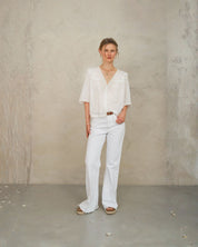 Model wearing white lace cotton blouse by Mabe Apparel with lace trim and V-necklin