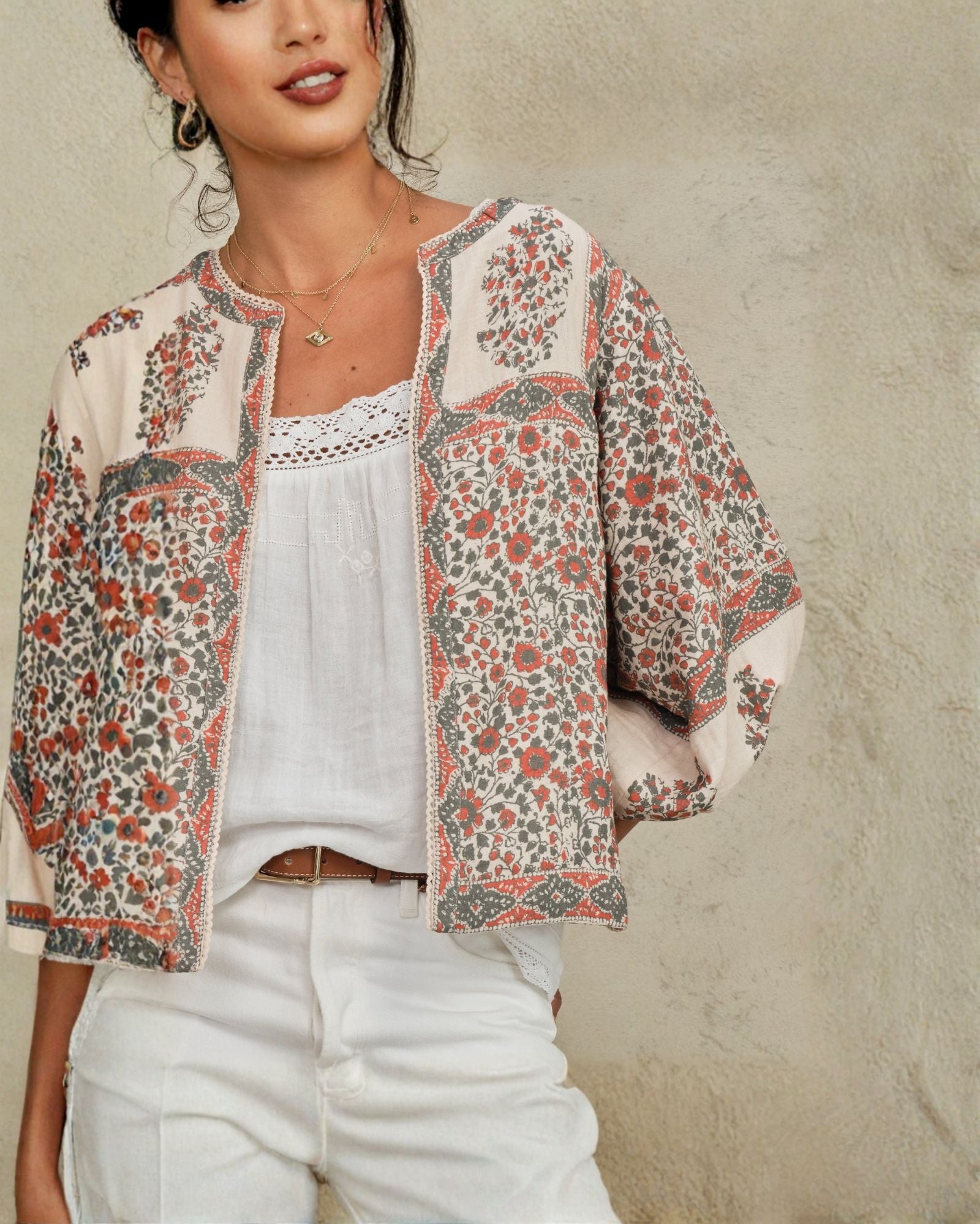 Detailed view of the collarless neckline and billowy sleeves on a Mabe Apparel floral print cotton jacket.