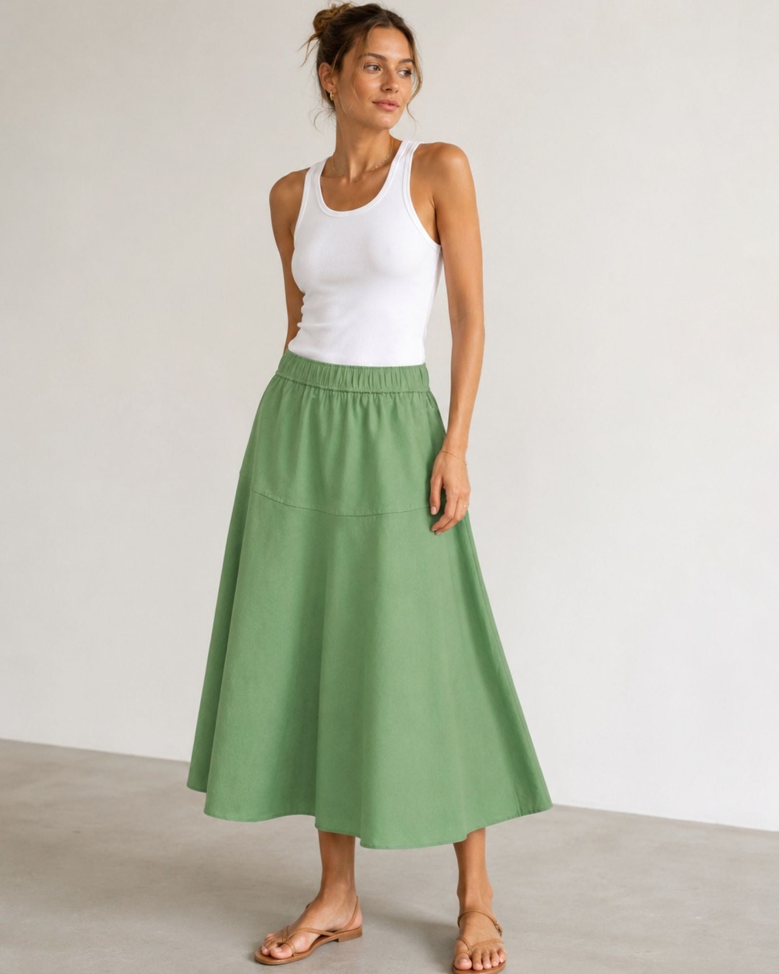 Woman wearing Mos Mosh MMEllaja sage green A-line midi skirt, styled with white tank top