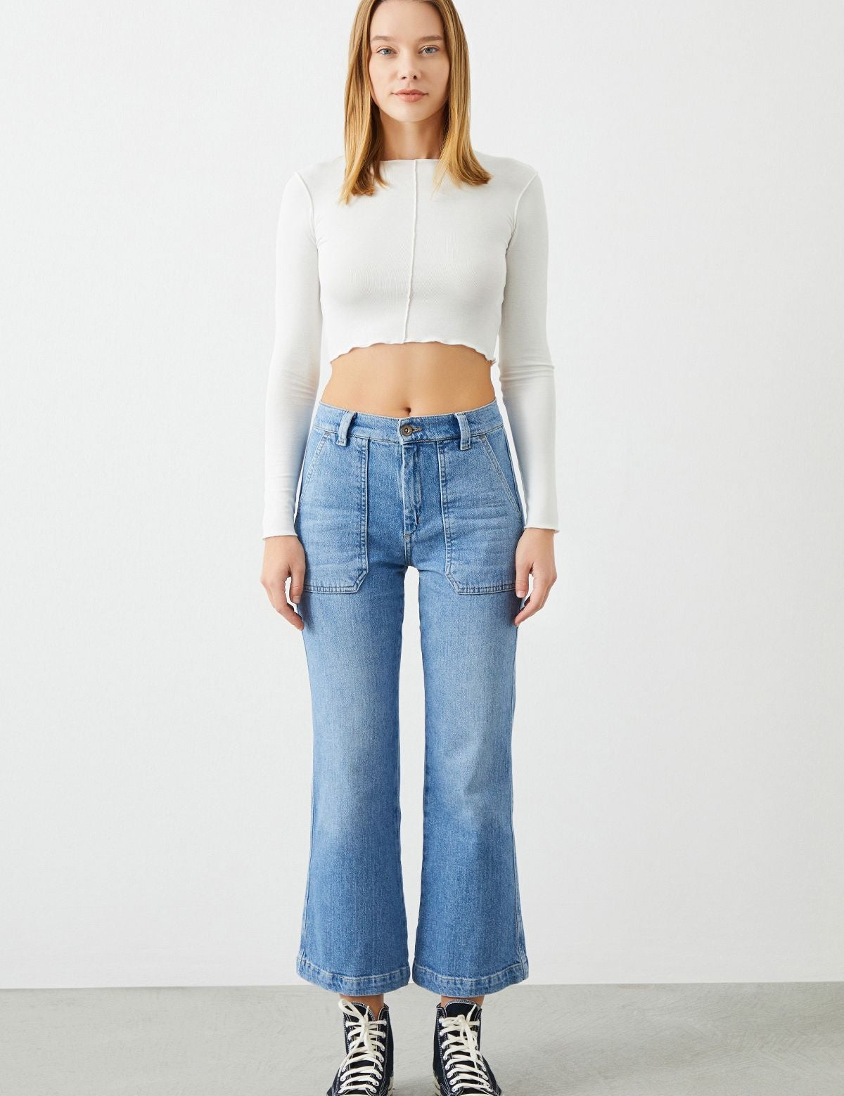 Model wearing Leyl Crop Flare Fit Jeans with white crop top by Sustainable Denim Brand Ra Denim, showcasing their trendy and flattering silhouette.