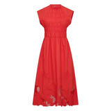 Model sitting wearing MMAria Mono Dress in Soft Coral, embroidered detail visible