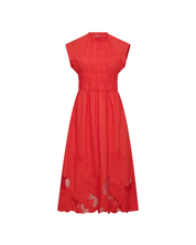 Model sitting wearing MMAria Mono Dress in Soft Coral, embroidered detail visible