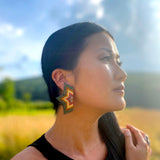 A woman wearing the Beaded Handwoven Large Half Star Earrings in Emerald