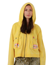 Front studio view of a model with the hood up on the washed yellow Amy cotton jacket, showcasing its straight silhouette.