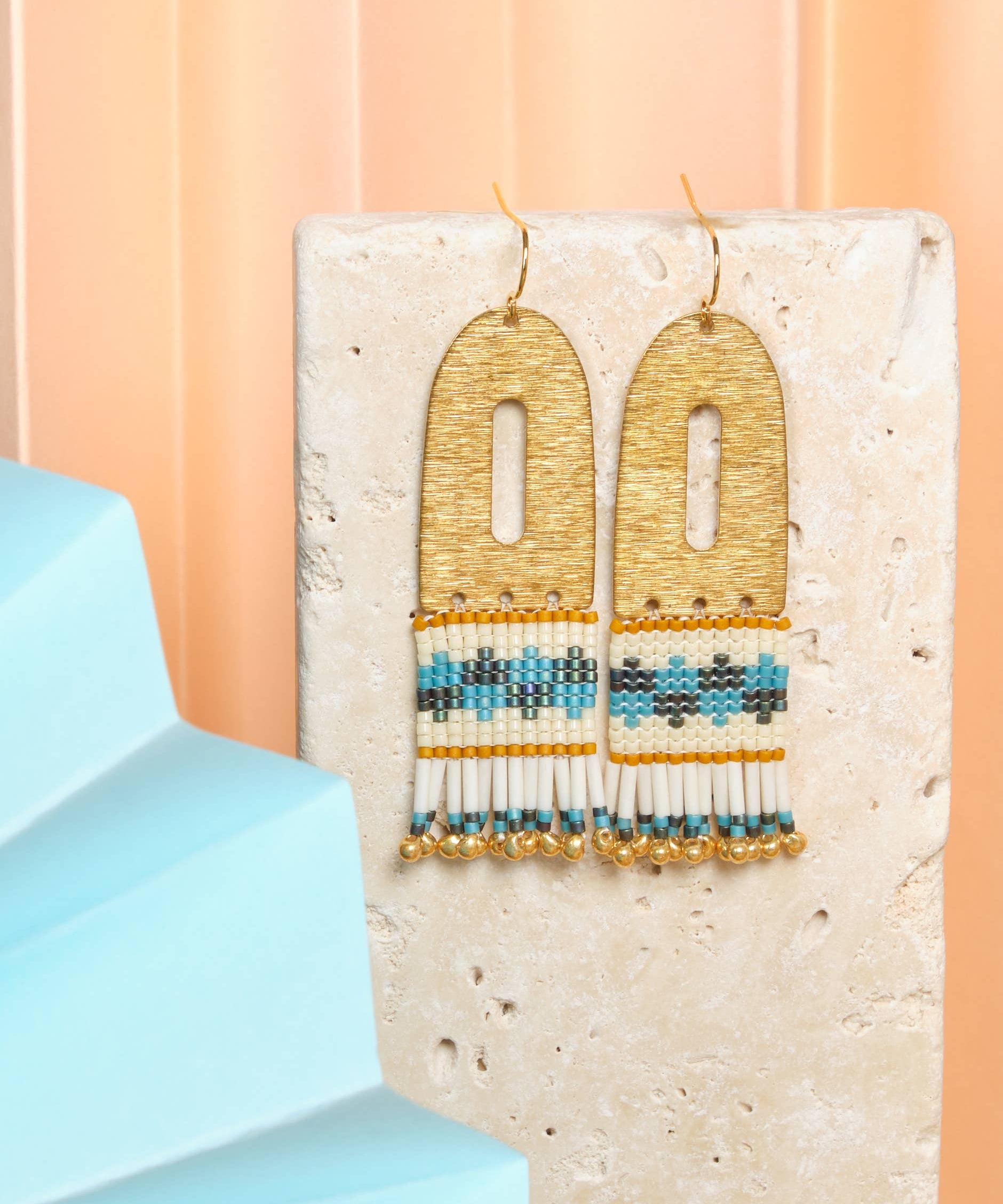 Vibrant Blue Aqua Miyuki glass beads and cream beads hang from a brass arch, creating a playful and stylish earring. 