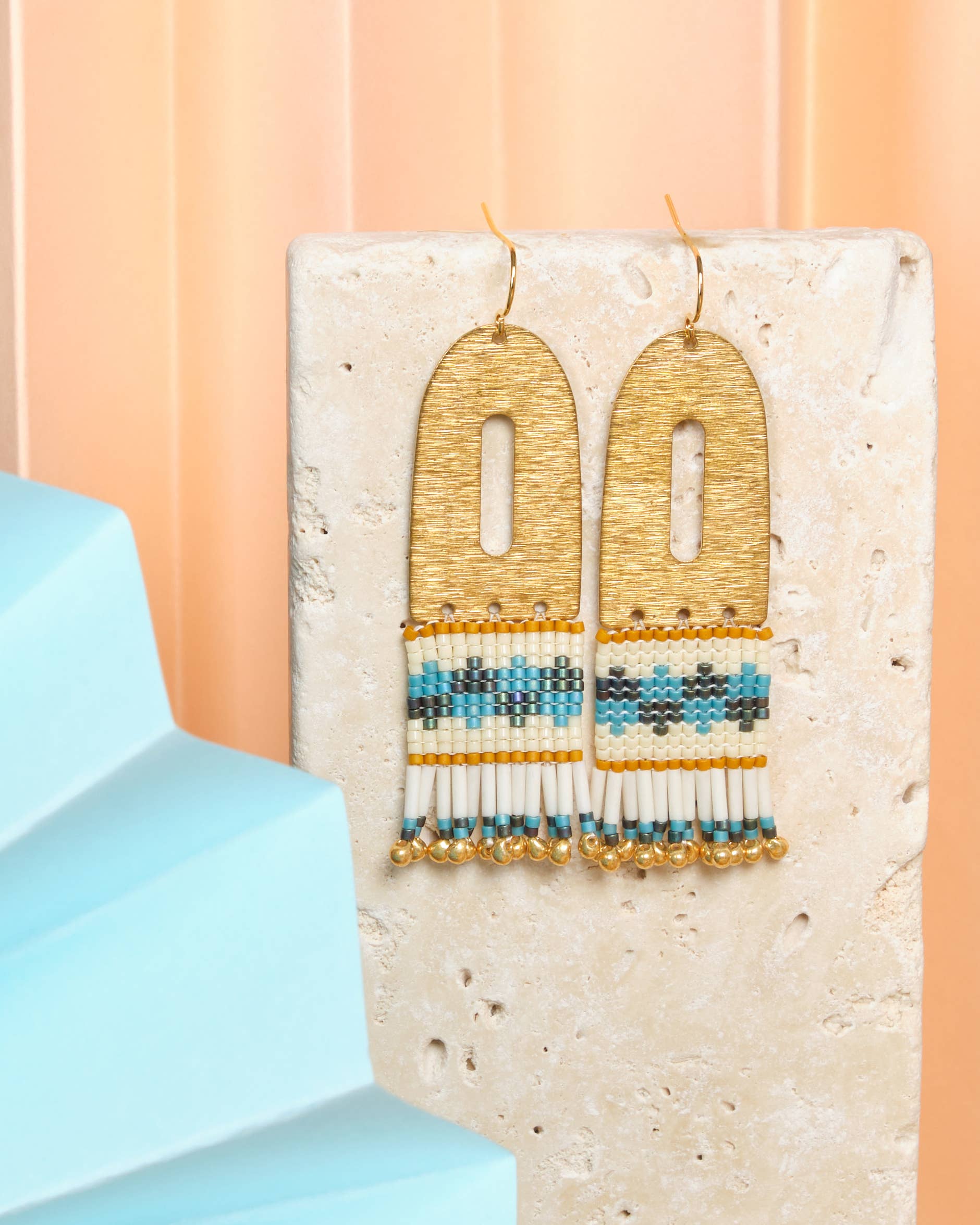 Vibrant Blue Aqua Miyuki glass beads and cream beads hang from a brass arch, creating a playful and stylish earring. 