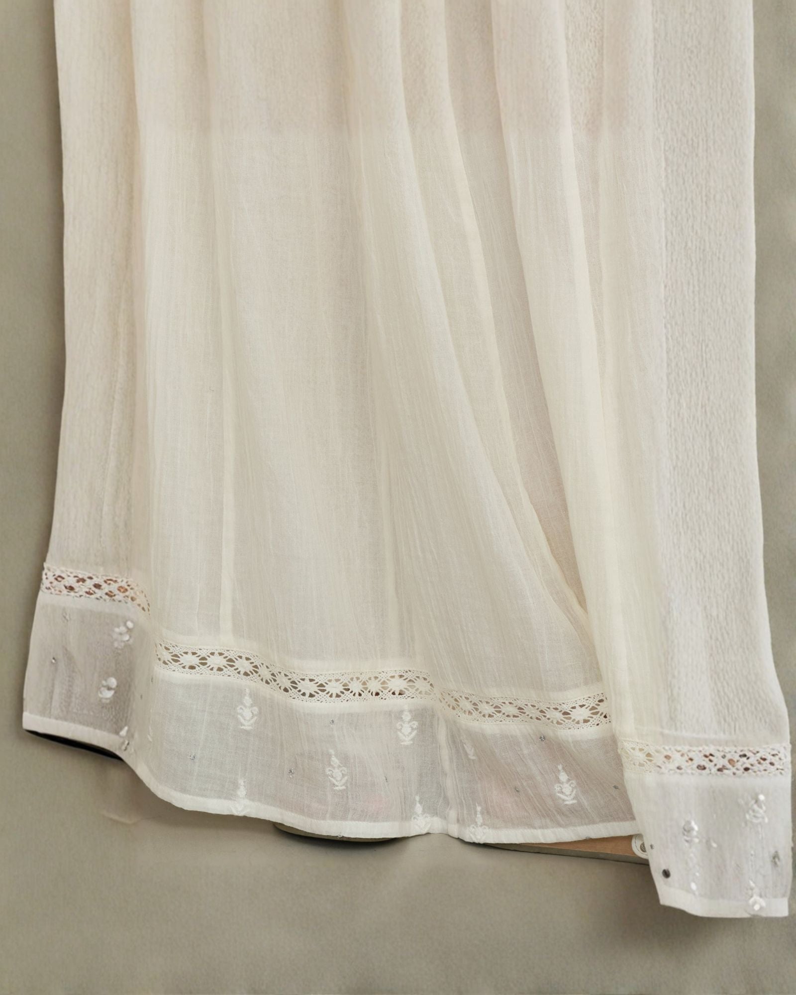 Detailed close-up of the openwork crochet lace and delicate embroidery on a cream Mabe Apparel skirt.