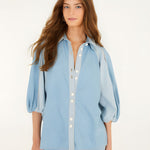 Front studio view of a model wearing the Farm Rio Bicolor Blue Fluid Denim Blouse, showcasing its light and mid-blue contrasting panels and relaxed fit.