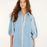 Front studio view of a model wearing the Farm Rio Bicolor Blue Fluid Denim Blouse, showcasing its light and mid-blue contrasting panels and relaxed fit.