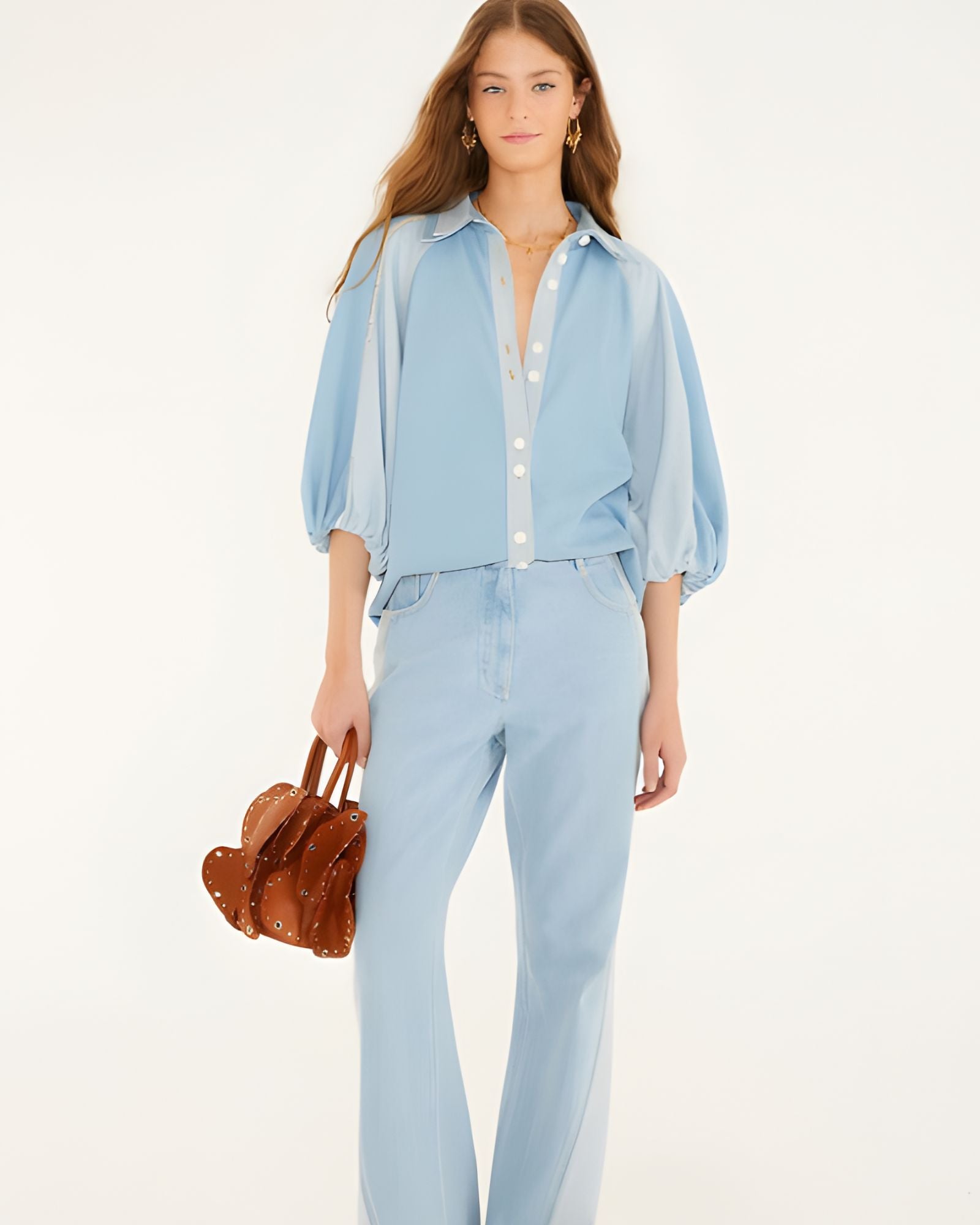 Full-length studio shot of a model styling the Farm Rio bicolor blue denim blouse with matching denim pants, holding a textured brown handbag.