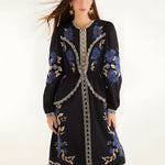 Full-length front view of a model wearing the Farm Rio Black Bold Flowers midi dress featuring blue floral embroidery and cream lace details.