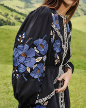 Close-up lifestyle view focusing on the billowing long sleeve of the Farm Rio dress, showcasing the vivid blue floral embroidery.