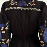 Close-up view of the Farm Rio Black Bold Flowers midi dress from behind, highlighting the intricate blue floral embroidery and geometric lace trim on the upper back yoke.