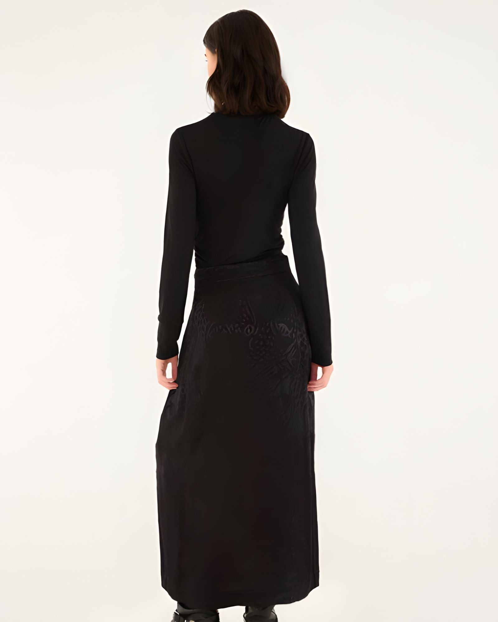 Full-length back studio view of a model wearing the Farm Rio black maxi skirt, displaying the clean floor-skimming silhouette.