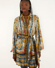 Front view of a model in a studio wearing the Farm Rio Blue Mosaic Garden belted mini dress with long sleeves.